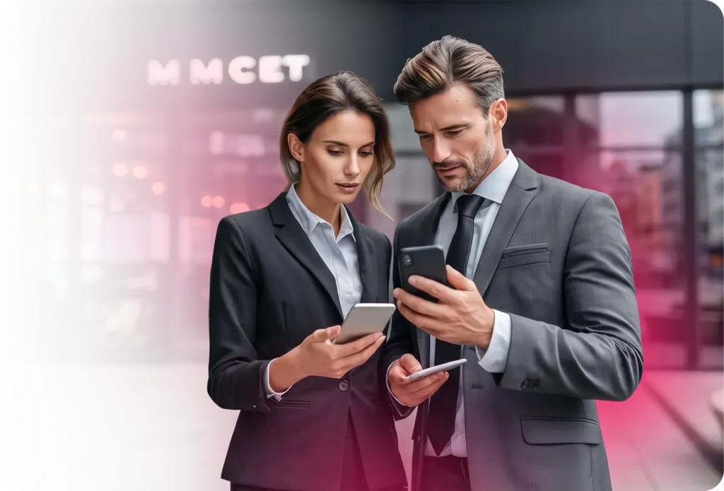 Dos ejecutivos de negocios con trajes de color gris oscuro a medida mirando sus smartphones frente a un edificio de oficinas moderno, que representan audiencias móviles profesionales alcanzables a través de la plataforma de publicidad empresarial de TrueSignal